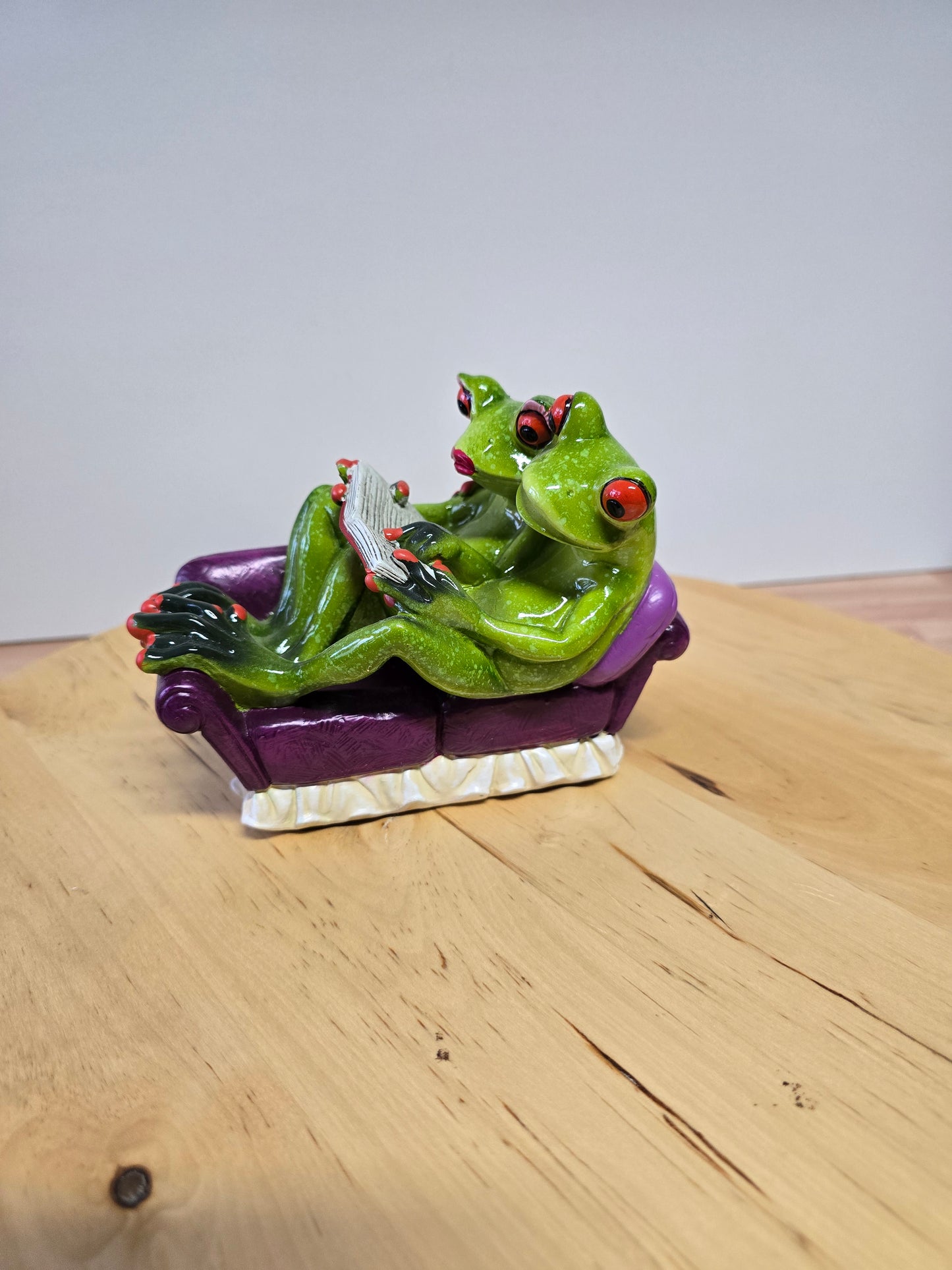 Froschpaar auf Sofa mit Buch