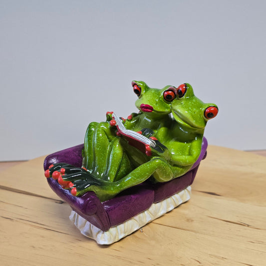 Froschpaar auf Sofa mit Buch